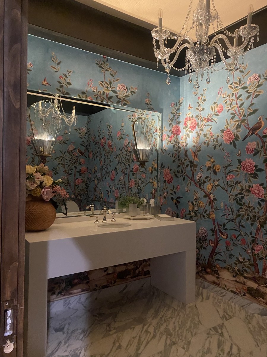 Powder room with blue floral chinoiserie wallpaper, a crystal chandelier, and a marble floor